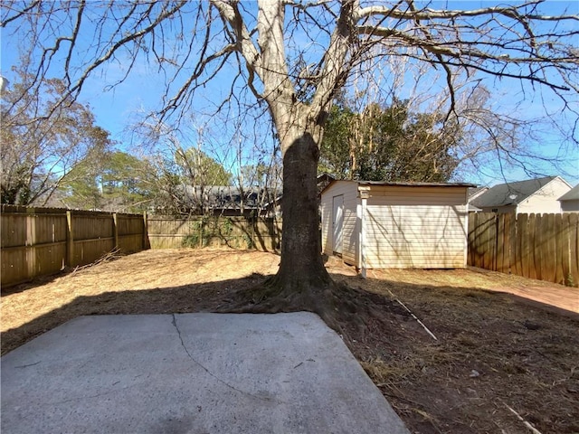 view of yard with a patio area, a fenced backyard, a storage shed, and an outbuilding