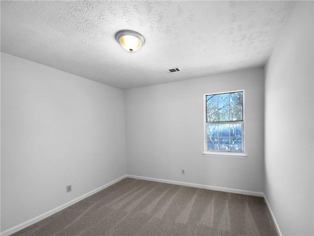 spare room featuring baseboards, a textured ceiling, visible vents, and carpet flooring