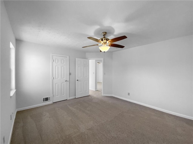 empty room with baseboards, visible vents, ceiling fan, a textured ceiling, and carpet floors