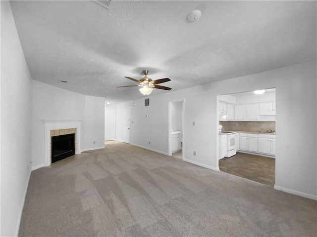 unfurnished living room featuring baseboards, a ceiling fan, a textured ceiling, carpet flooring, and a fireplace