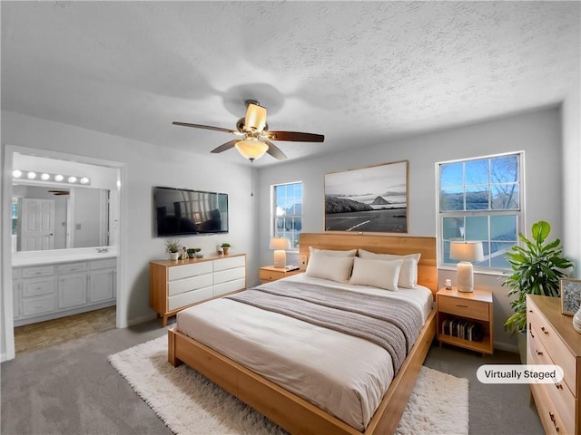 bedroom with a textured ceiling, ceiling fan, carpet flooring, and connected bathroom