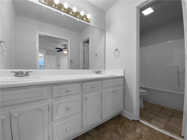 full bath featuring toilet, double vanity, a ceiling fan, and a sink