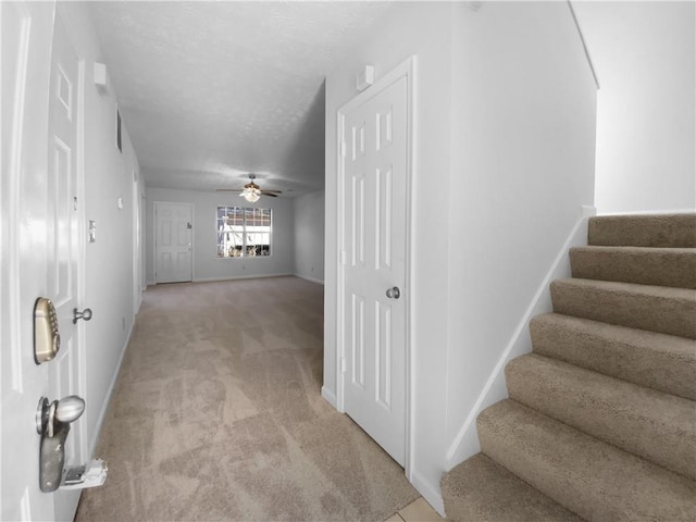 hallway with baseboards, light carpet, stairway, and a textured ceiling