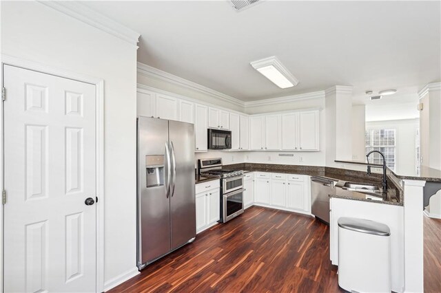 kitchen featuring a sink, dark wood finished floors, a peninsula, and stainless steel appliances