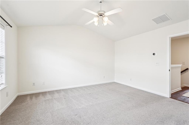 carpeted empty room featuring vaulted ceiling, baseboards, a ceiling fan, and visible vents