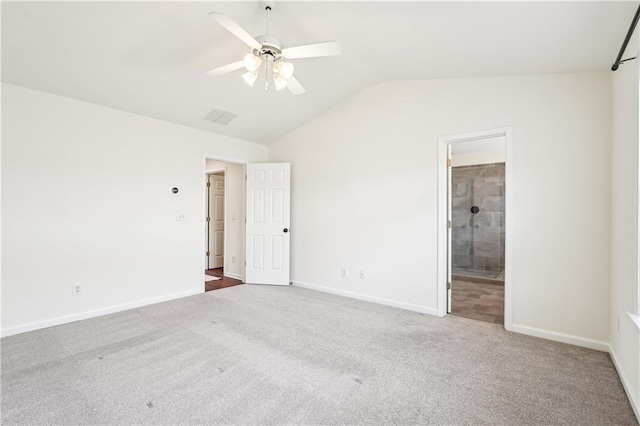 unfurnished bedroom with visible vents, lofted ceiling, baseboards, connected bathroom, and carpet flooring