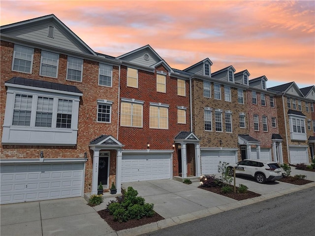 multi unit property with brick siding, a garage, and driveway