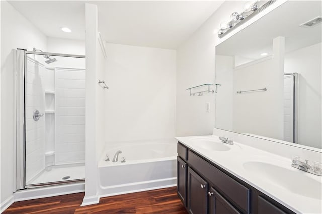 full bathroom featuring a stall shower, visible vents, a sink, and wood finished floors