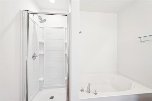 bathroom with a stall shower and a bath