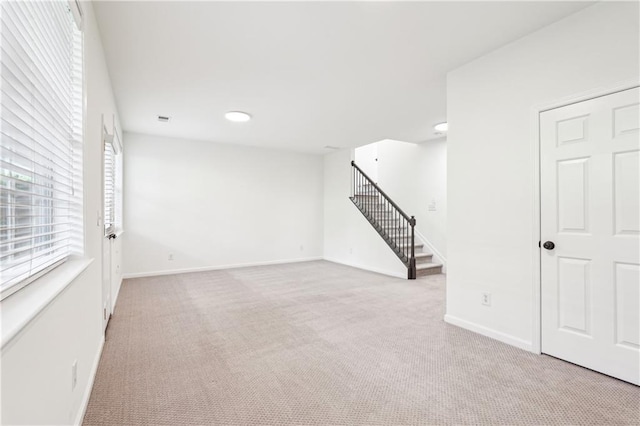 unfurnished living room with recessed lighting, baseboards, stairs, and light colored carpet