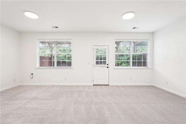 spare room with a wealth of natural light, light carpet, and visible vents