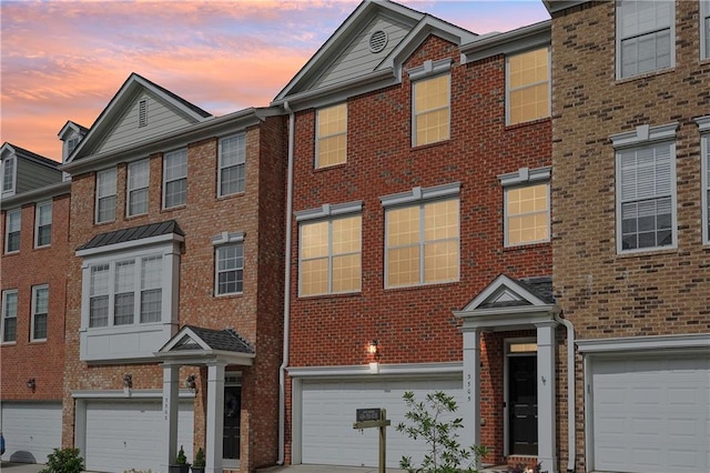 townhome / multi-family property with brick siding, an attached garage, and driveway