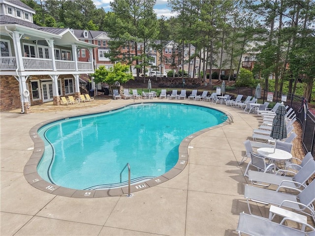 community pool featuring french doors, fence, and a patio area