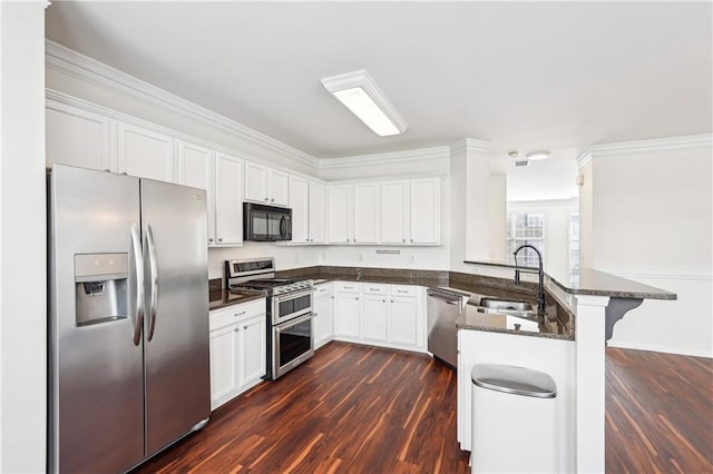 kitchen featuring a kitchen bar, a sink, white cabinets, a peninsula, and stainless steel appliances