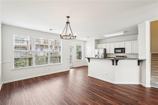 kitchen featuring a kitchen bar, dark countertops, dark wood finished floors, baseboards, and stainless steel appliances