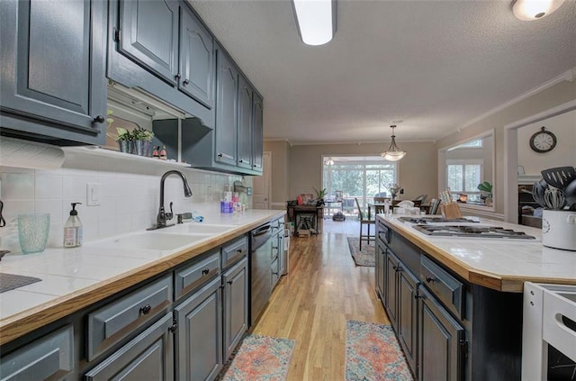 kitchen with backsplash, sink, crown molding, hanging light fixtures, and stainless steel appliances