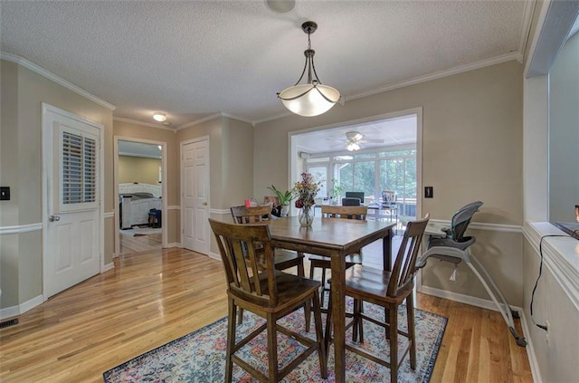 dining area with crown molding, a textured ceiling, and light hardwood / wood-style flooring