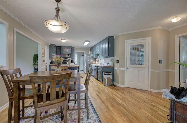 dining area featuring a textured ceiling, light hardwood / wood-style flooring, and ornamental molding