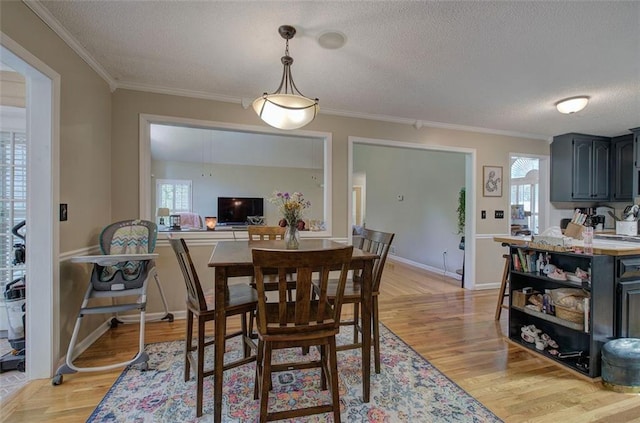 dining area with crown molding, light wood-type flooring, and a textured ceiling