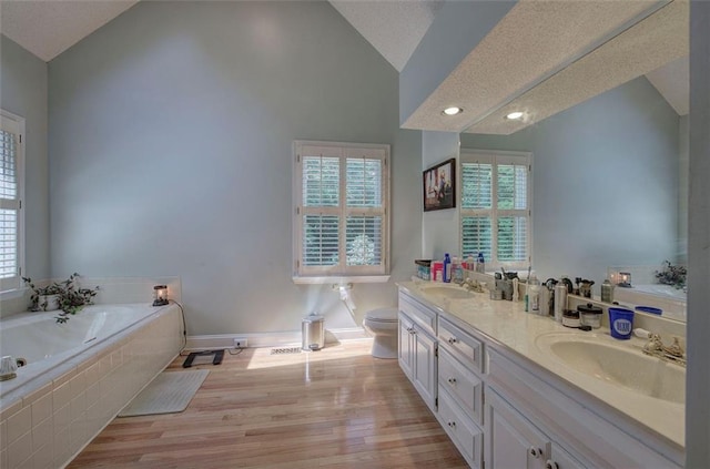 bathroom featuring hardwood / wood-style floors, a textured ceiling, lofted ceiling, toilet, and vanity