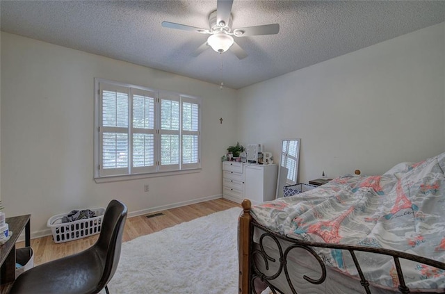 bedroom with ceiling fan, light wood-type flooring, and a textured ceiling