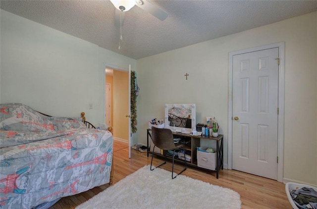 bedroom with ceiling fan, light wood-type flooring, and a textured ceiling