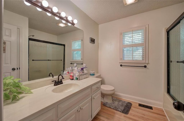 full bathroom with wood-type flooring, a textured ceiling, combined bath / shower with glass door, toilet, and vanity