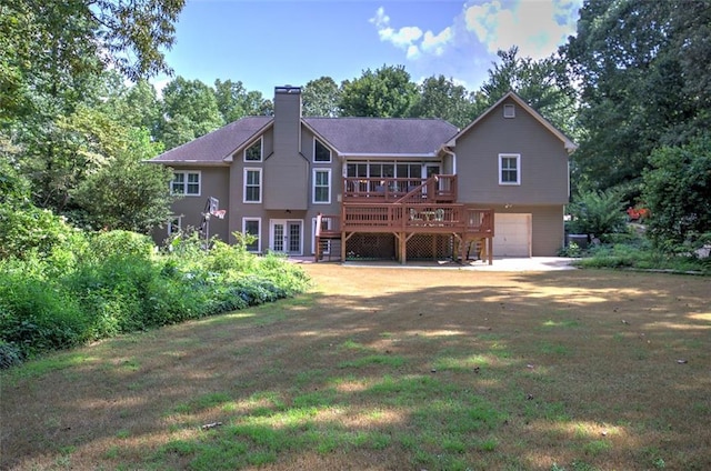 rear view of property featuring french doors, a yard, a garage, and a wooden deck