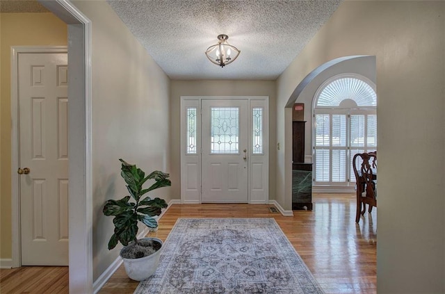 foyer entrance featuring a chandelier, a textured ceiling, and light hardwood / wood-style floors