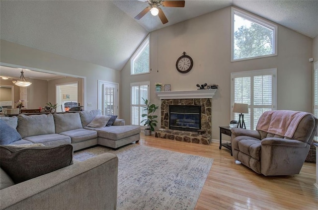 living room with ceiling fan, light hardwood / wood-style floors, a fireplace, and high vaulted ceiling