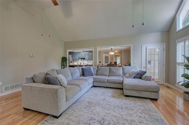 living room with ceiling fan, wood-type flooring, a textured ceiling, and high vaulted ceiling