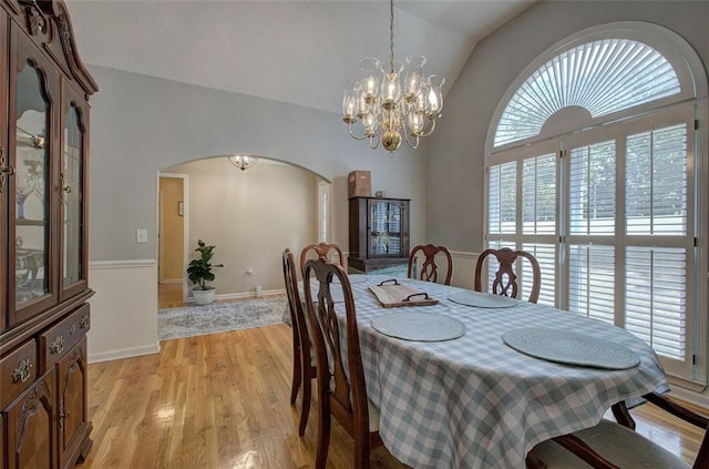 dining space featuring light hardwood / wood-style floors, lofted ceiling, and an inviting chandelier