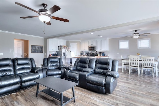 living room featuring ornamental molding, light hardwood / wood-style flooring, and ceiling fan