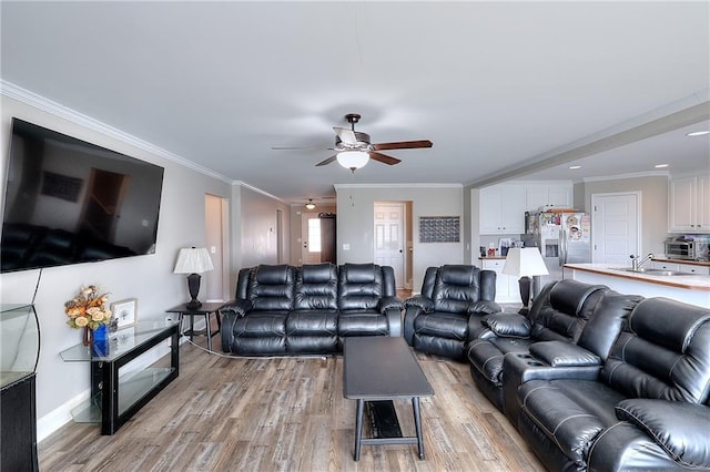 living room featuring sink, crown molding, light hardwood / wood-style floors, and ceiling fan