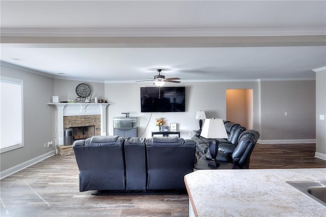 living room featuring ceiling fan, hardwood / wood-style flooring, a fireplace, crown molding, and sink