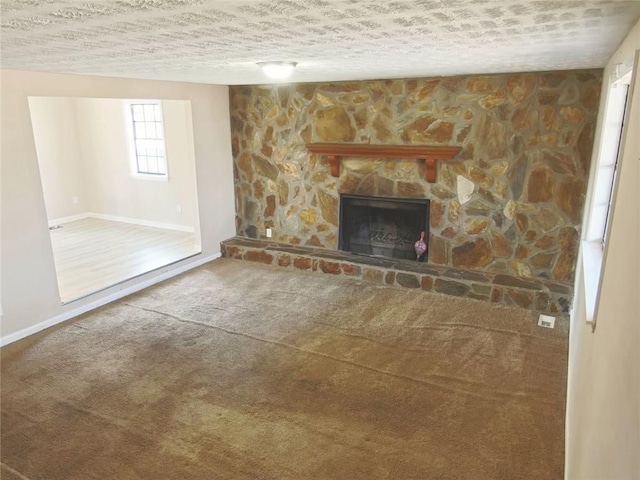 unfurnished living room with carpet flooring, a stone fireplace, and a textured ceiling