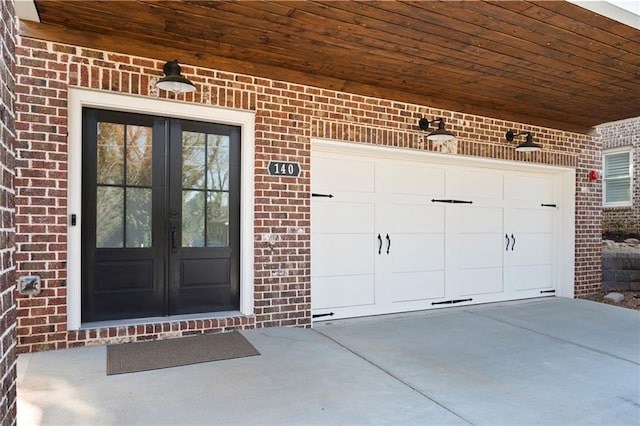 entrance to property featuring brick siding, french doors, and concrete driveway