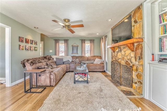285 Skeet Shoot Rd, Dallas, GA 30132 - living room with light wood-style flooring, ceiling fan, a fireplace, baseboards, and a textured ceiling