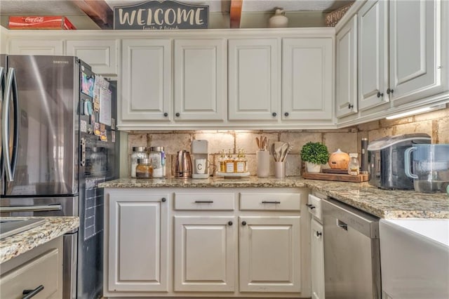 kitchen with tasteful backsplash, white cabinets, stainless steel appliances, and light stone counters