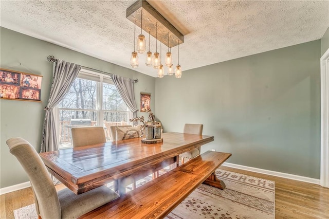 dining space with wood finished floors, baseboards, and a textured ceiling