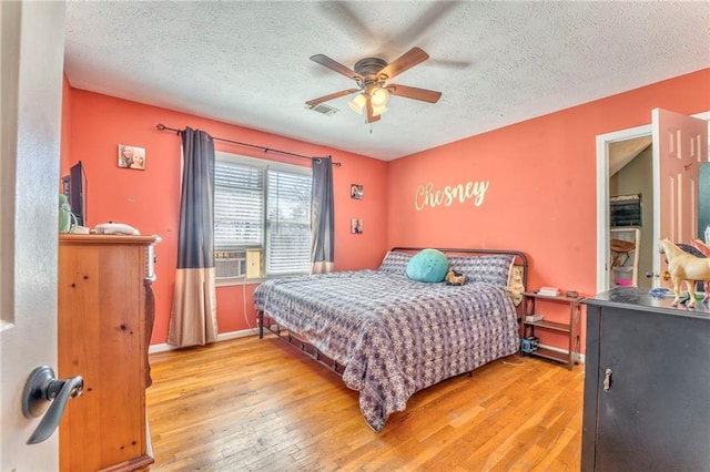 bedroom with visible vents, cooling unit, a textured ceiling, and wood-type flooring