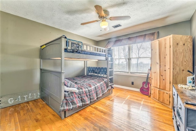 bedroom with visible vents, a textured ceiling, baseboards, and hardwood / wood-style floors