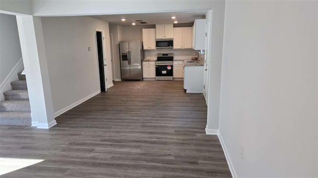 kitchen featuring white cabinets, decorative backsplash, stainless steel appliances, and dark wood-type flooring