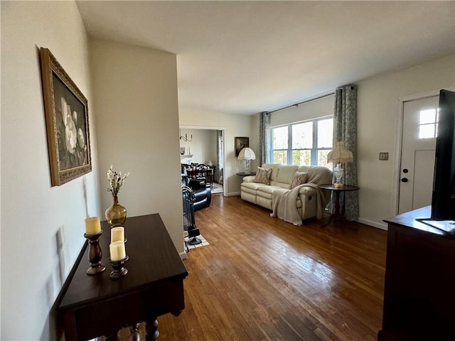 living area featuring baseboards and dark wood-style floors