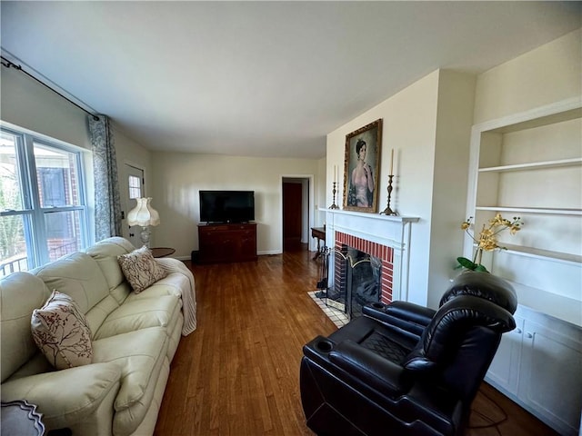 living area featuring built in features, a fireplace, and wood finished floors