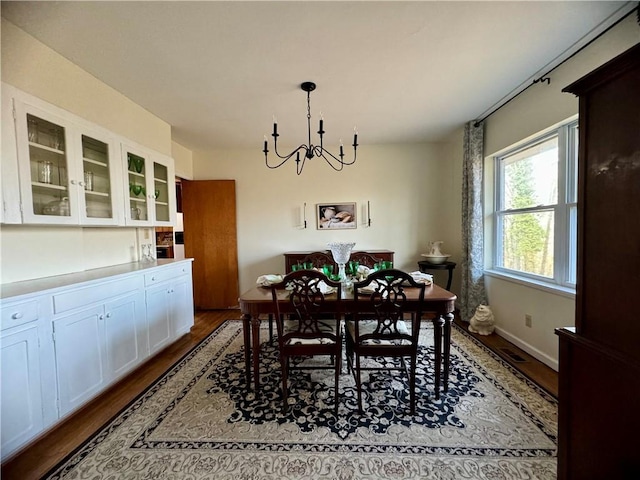 dining area featuring an inviting chandelier, wood finished floors, and baseboards