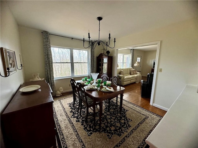 dining space with baseboards, an inviting chandelier, and light wood finished floors