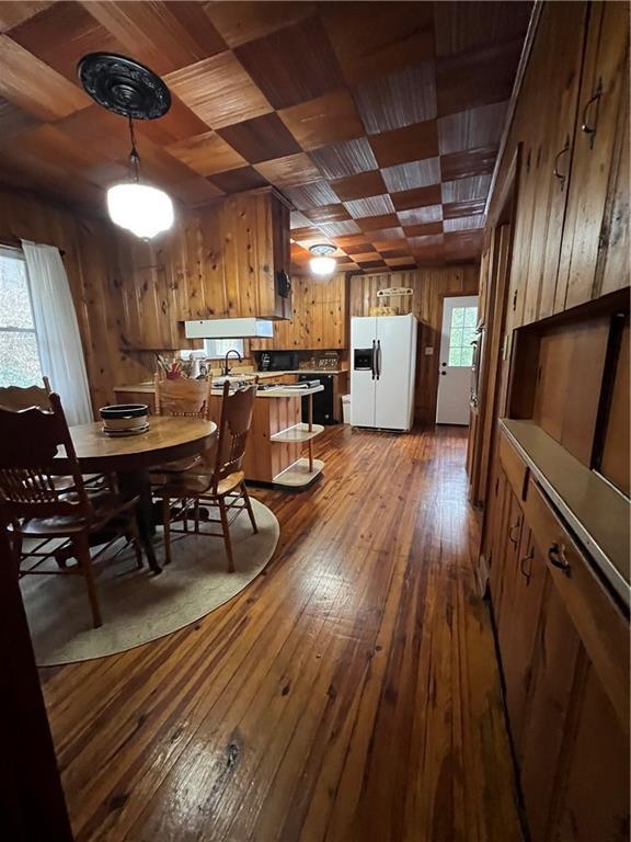 dining area featuring wood-type flooring, wooden walls, and wood ceiling