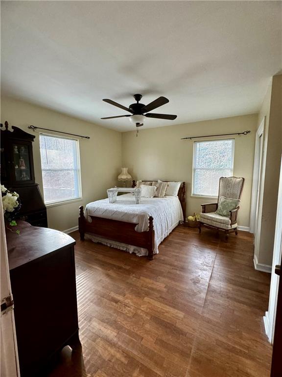 bedroom featuring multiple windows, dark wood-type flooring, and baseboards