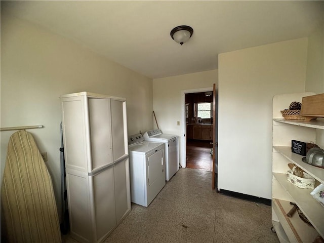 clothes washing area featuring laundry area, washing machine and dryer, and baseboards